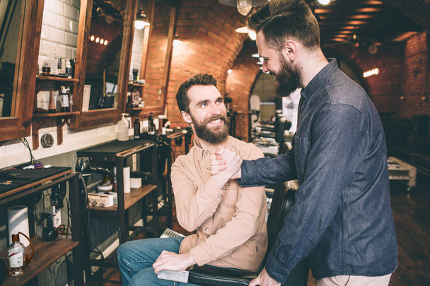 Two guys are shaking each others hands. Tey are happy to meet in a barbershop. - Foto, Imagem