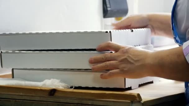 Las manos femeninas pliegan las cajas de pizza en la cocina
 - Imágenes, Vídeo
