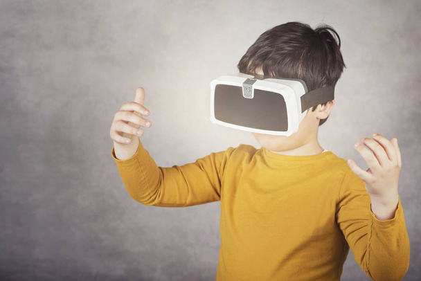 niño jugando con gafas de realidad virtual sobre fondo gris
 - Foto, imagen