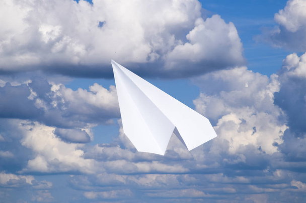 Avión de papel blanco en un cielo azul con nubes. El símbolo del mensaje en el mensajero
 - Foto, imagen