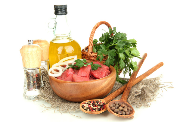 Raw beef meat in bowl with herbs, spices and cooking oil isolated on white - Foto, Imagen
