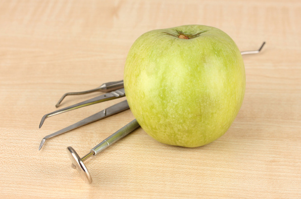 Green apple and dental tools on wooden background - Fotoğraf, Görsel