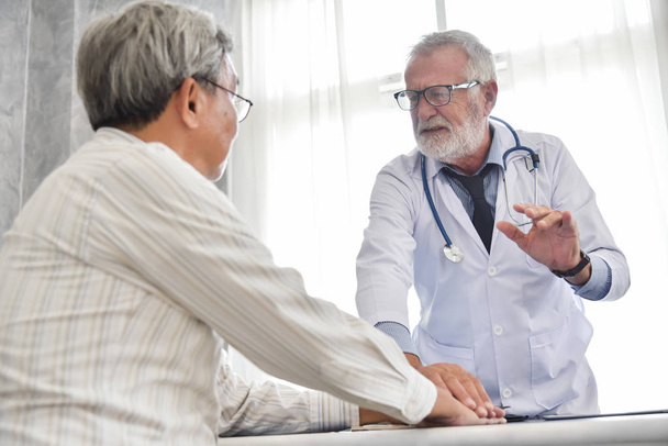 Senior male Doctor is discussing with Asian male patient. - Φωτογραφία, εικόνα