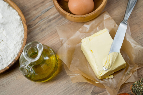 close-up photo of fresh egg in wooden plate with olive oil, flour and butter on table background   - Foto, immagini