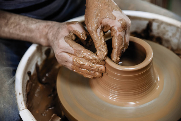 Керамика. Мастер за гончарным колесом, производит глиняный сосуд
 - Фото, изображение