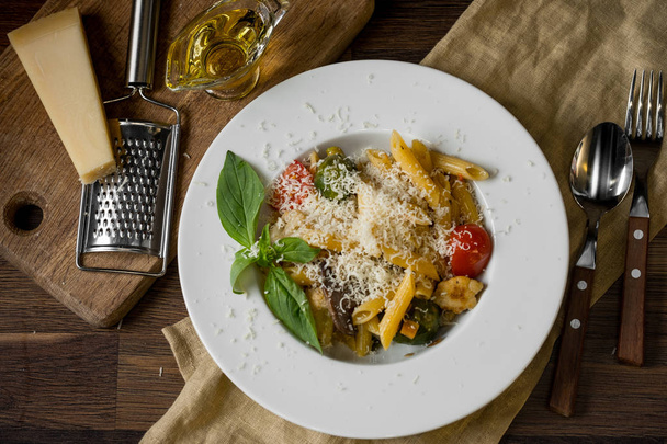 close-up photo of tasty pasta with cheese and green basilica leaves on plate background - Foto, Imagen