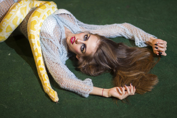 Sensual woman relax with albino python. Snake crawl on woman with long hair. Beauty model with makeup face and yellow serpent. Danger temptation and desire concept. - Zdjęcie, obraz