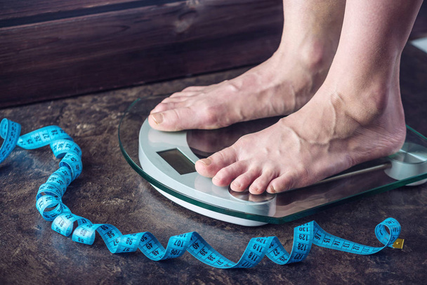 女性の足は、暗い背景に体重管理のための電子秤の上に立って。スポーツ トレーニング、ダイエットの概念 - 写真・画像