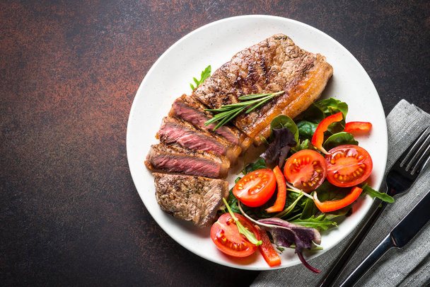 Grilled beef striploin steak with fresh salad top view. - Photo, image