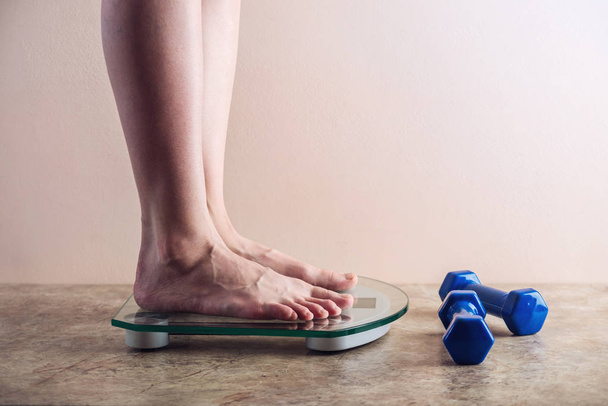 Pés femininos em pé em balanças eletrônicas para controle de peso em fundo claro. Conceito de treinamento esportivo, dietas
 - Foto, Imagem