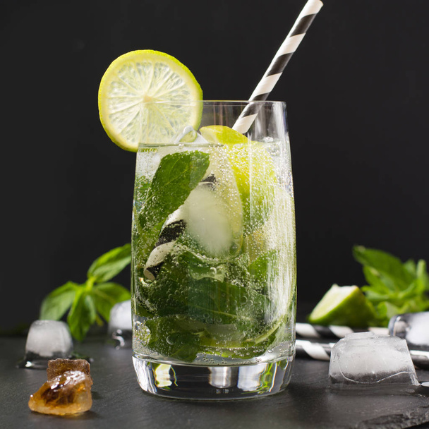 Mojito cocktail in glass on black table. Low key photo. Close up. - Фото, изображение