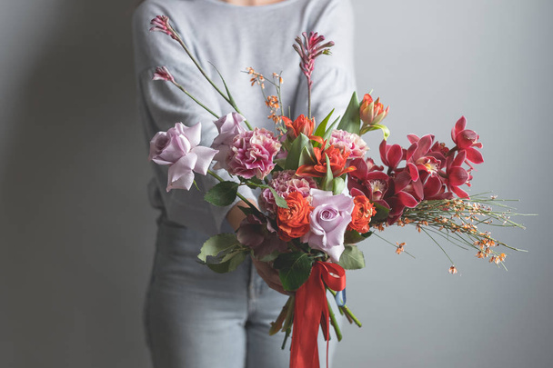 photo of fashion female holding bouquet of beautiful flowers on grey background - Zdjęcie, obraz