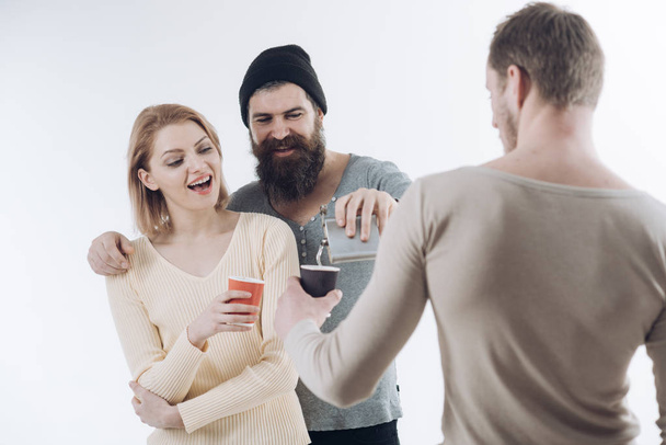 Guys hold cup, flask with alcohol, speak. Company of cheerful friends spend leisure with drinks. Fun and leisure concept. Communication, friendship, fun. Men, woman on smiling faces, white background. - 写真・画像