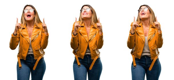 Beautiful young woman happy and surprised cheering expressing wow gesture pointing up over white background - Fotoğraf, Görsel