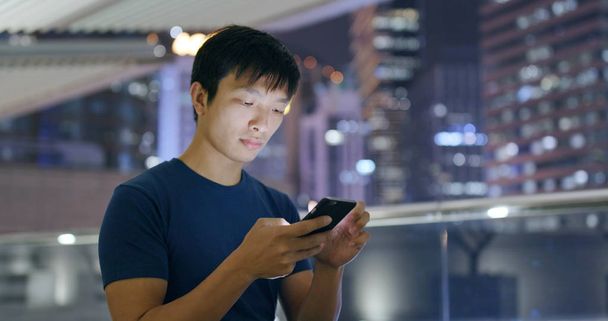 Man using smartphone in city at night  - Foto, Bild