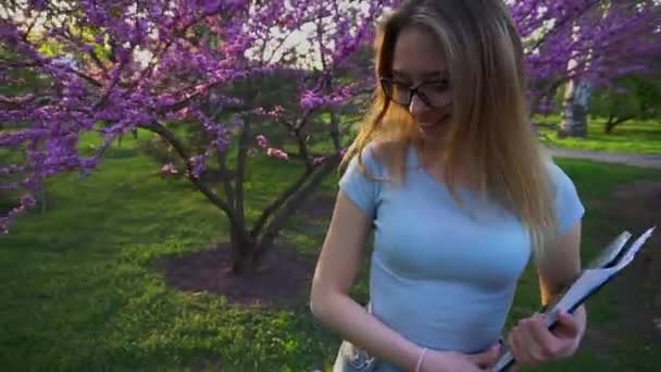 Landschap ontwerper wandelen met documenten in de buurt van bloeiende boom, slow-motion. - Video
