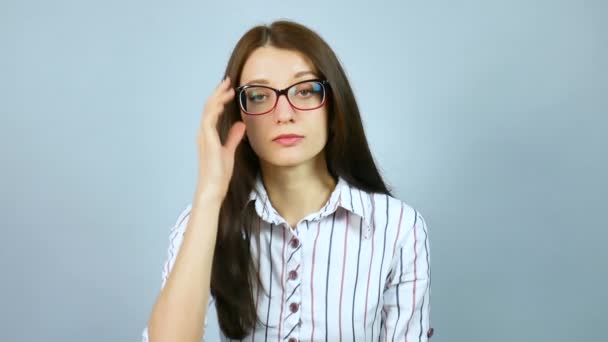 Fiatal szigorú igényes női tanár néz a kamerába, a stúdió a szürke háttér optikai szemüveg viselése. - Felvétel, videó