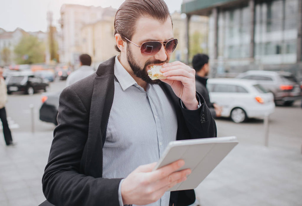 Busy man is in a hurry, he does not have time, he is going to eat snack on the go. Worker eating, drinking coffee, talking on the phone, at the same time. Businessman doing multiple tasks - 写真・画像