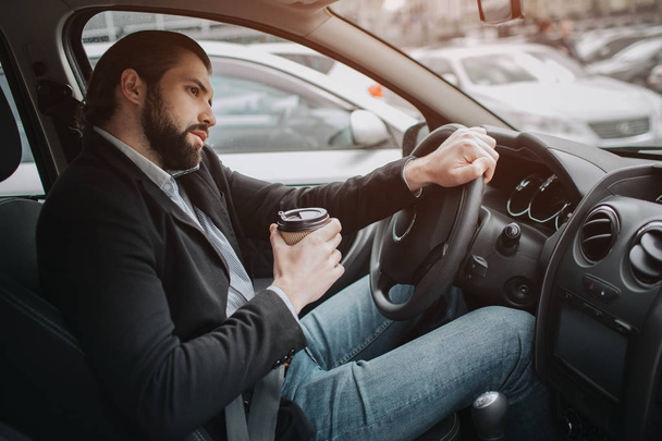 The driver going on the road, speaking on the phone, working with documents at the same time. Businessman doing multiple tasks. Multitasking business person. - 写真・画像