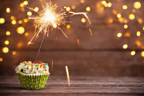 cupcake with sparkler on old wooden background - Photo, image