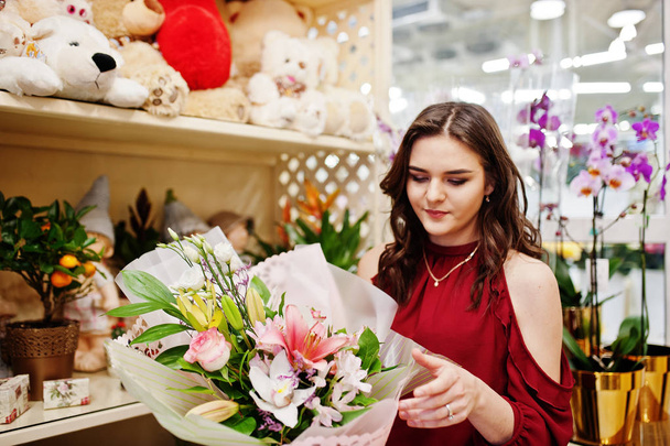 Brunette girl in red buy flowers at flower store. - Photo, image