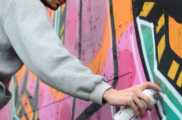 グレーのパーカーで若い男塗料落書き壁にピンクとグリーン色の雨の天気の - 写真・画像