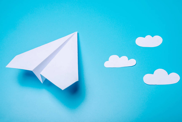 Valkoinen paperi origami lentokone sijaitsee pastelli sininen tausta, ylhäältä
. - Valokuva, kuva