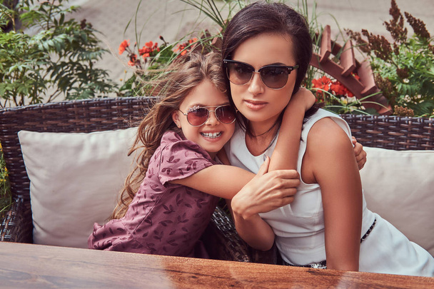 Retrato de mãe na moda e sua linda filha durante um tempo em um café ao ar livre
. - Foto, Imagem