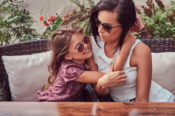 Retrato de la madre de moda y su encantadora hija durante un tiempo en un café al aire libre
. - Foto, imagen