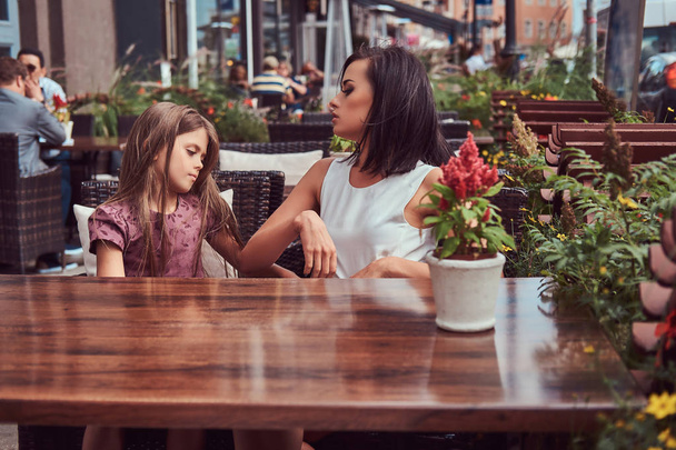 Porträt der modischen Mutter und ihrer schönen Tochter während einer Zeit in einem Outdoor-Café. - Foto, Bild