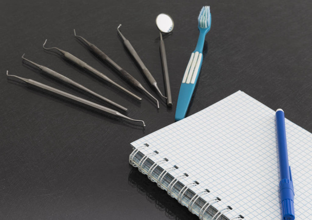 op een grijze achtergrond is een notebook, tandheelkundige instrumenten - Foto, afbeelding