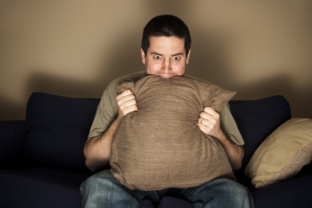 Mann beißt vor Angst auf Kissen beim Fernsehen - Foto, Bild