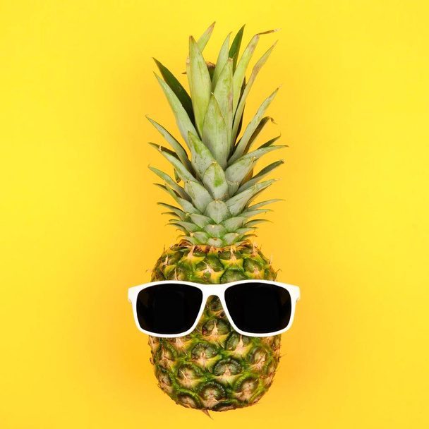 Hipster pineapple with sunglasses. Top view against a yellow background. Minimal summer concept. - Zdjęcie, obraz
