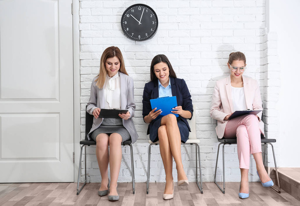 Jovens mulheres à espera de entrevista de emprego, dentro de casa
 - Foto, Imagem