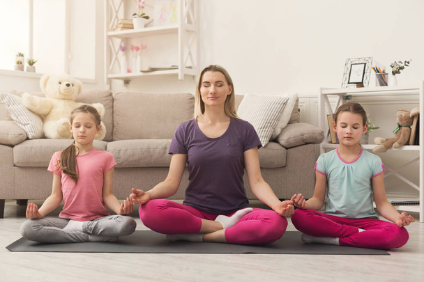 Young woman and daughters doing yoga exercise at home - Φωτογραφία, εικόνα