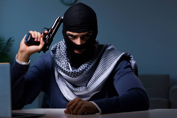 Terrorverdächtiger Einbrecher mit Waffe arbeitet am Computer - Foto, Bild