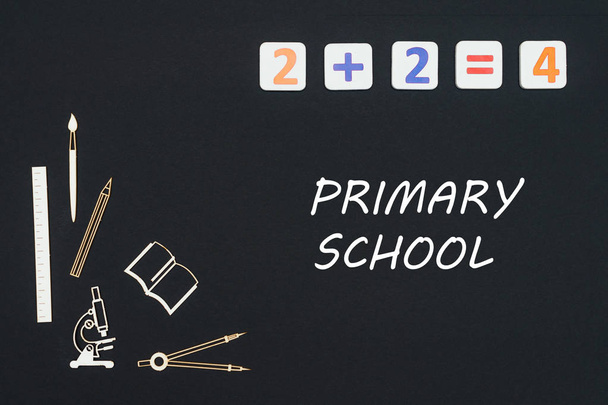 Fournitures scolaires placées sur fond noir avec texte école primaire
 - Photo, image