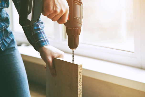 close-up view of man's hands drilling wooden plank - Photo, image