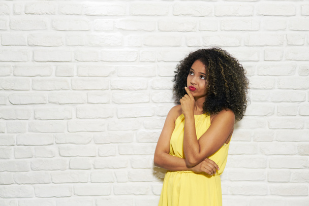 Выражение лица молодой чёрной женщины на кирпичной стене
 - Фото, изображение