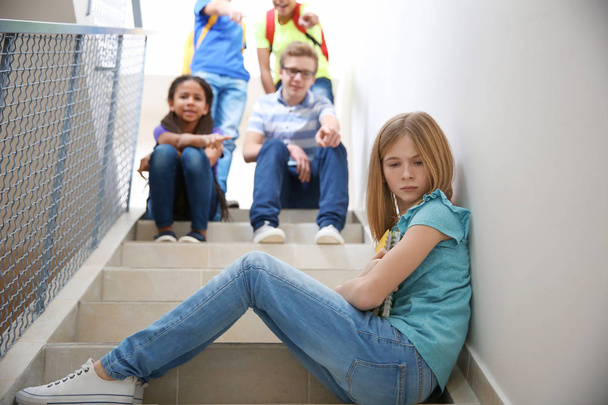 Bullied teenage girl on stairs at school - Foto, afbeelding