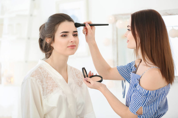 Professional makeup artist working with young woman in salon - Foto, imagen