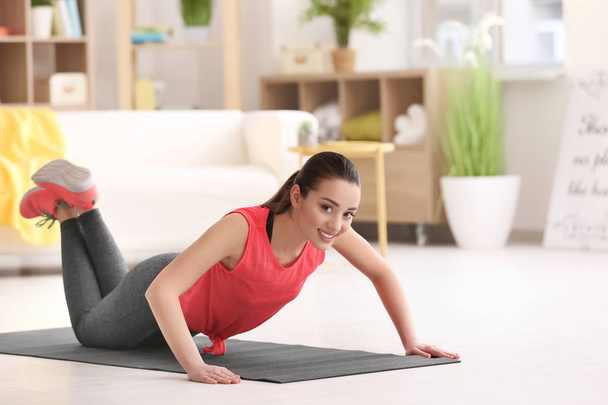 Beautiful young woman doing fitness exercise at home - Photo, Image