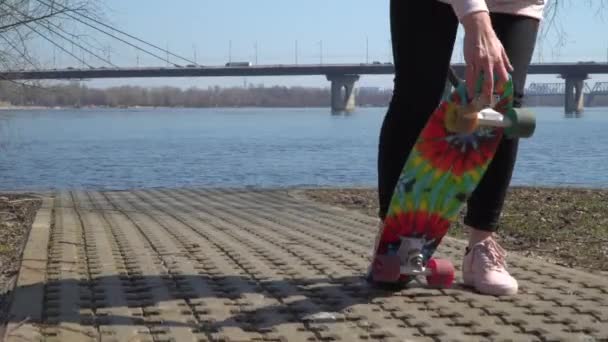 Stylish girl with skateboard at the river background - Кадры, видео