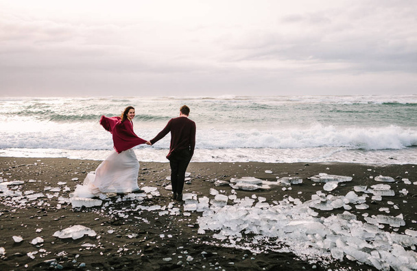 Beautiful Newlyweds is walking on Black Sand Beach, Iceland. Artwork - Foto, afbeelding