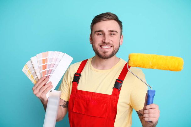 Male decorator with palette and roller on color background - Valokuva, kuva