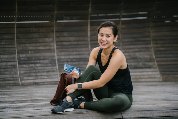 Portrait of an attractive, young Chinese Asian woman dressed in sporty, active wear with phone.  - Photo, Image