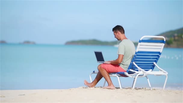 Mladý muž s tabletovým počítačem během dovolené na tropické pláži - Záběry, video