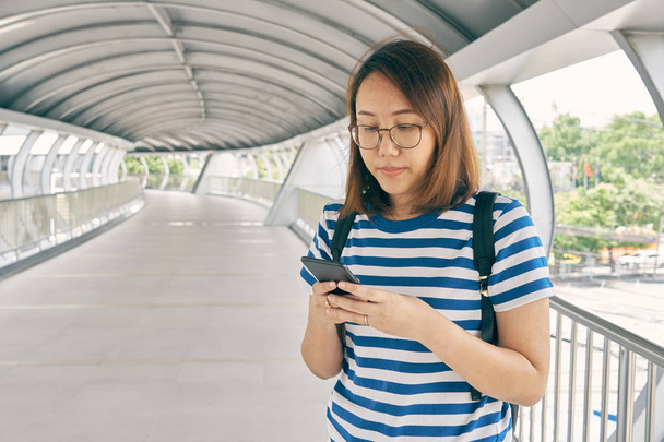 Toeristische meisje Aziaten leeftijd van 25-35 gebruiken smartphones te vinden bestemmingen. Plaatsen van belang vinden. Het gebruik van smartphones is vandaag zeer belangrijk om te reizen van vandaag. gebruik als achtergrond reizen concept. - Foto, afbeelding