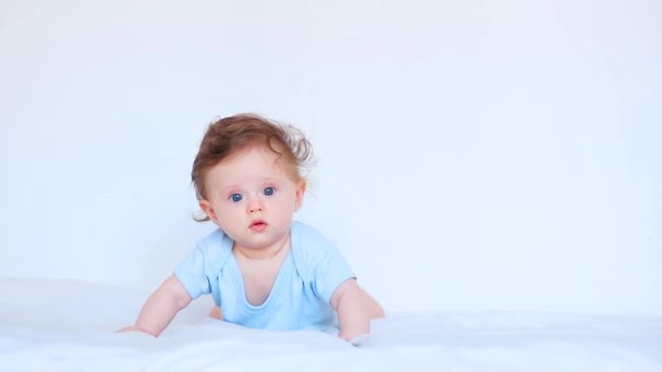 Kleines Baby liegt in heller Kleidung in einem Bett - Filmmaterial, Video