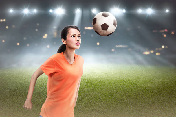 Young asian soccer player woman heading ball on field - Foto, imagen